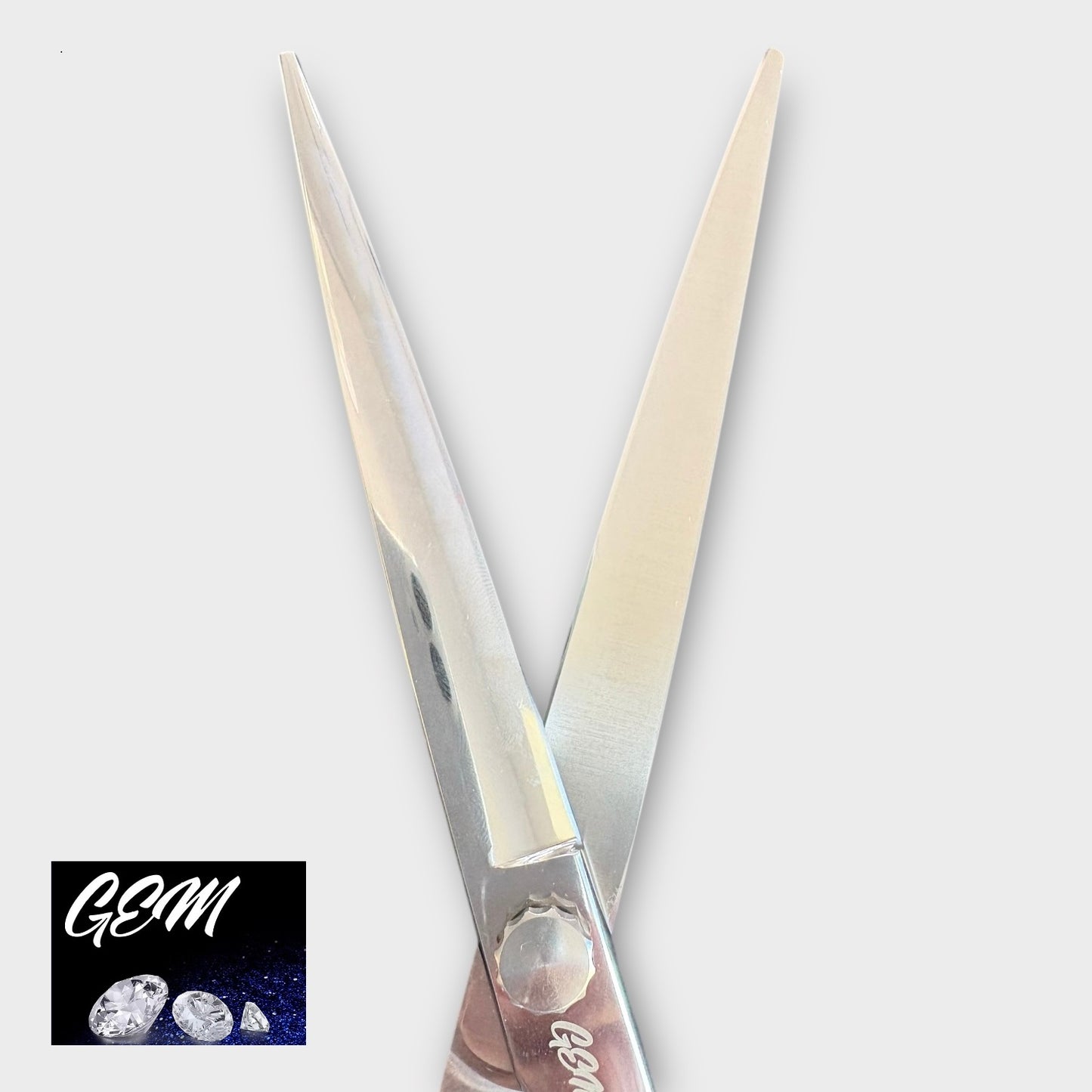 A pair of GEM Supreme Straights 7.5" Scissors is displayed on a light gray background, with the GEM logo and three gemstones in white on a dark square in the bottom left corner.