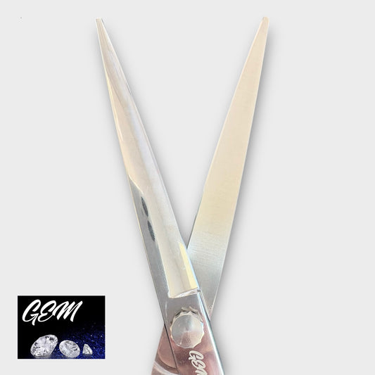A pair of GEM Supreme Straights 7.5" Scissors is displayed on a light gray background, with the GEM logo and three gemstones in white on a dark square in the bottom left corner.
