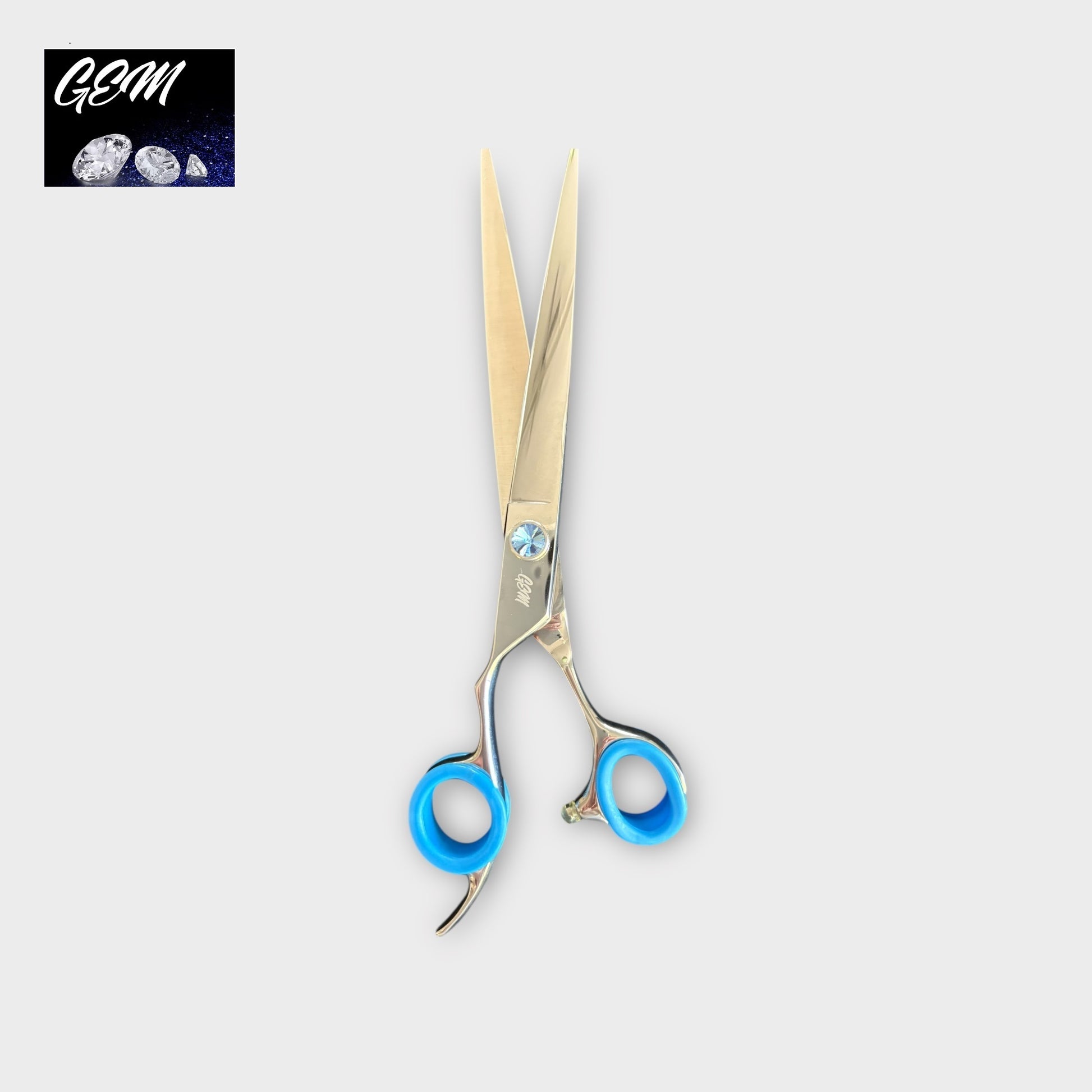 The GEM Blue Stone Straights 7.5" Lefthanded Scissors, featuring silver blades and blue finger grips, are shown on a light grey background with the GEM logo and illustrated gemstones in the top left corner.
