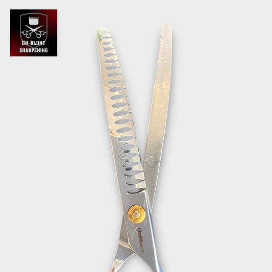A pair of UnBlunt Curved Chunkers 7" scissors with serrated blades and a gold screw; the top left corner displays a logo showing a razor, comb, and scissors above the text "UN-BLUNT SHARPENING.
