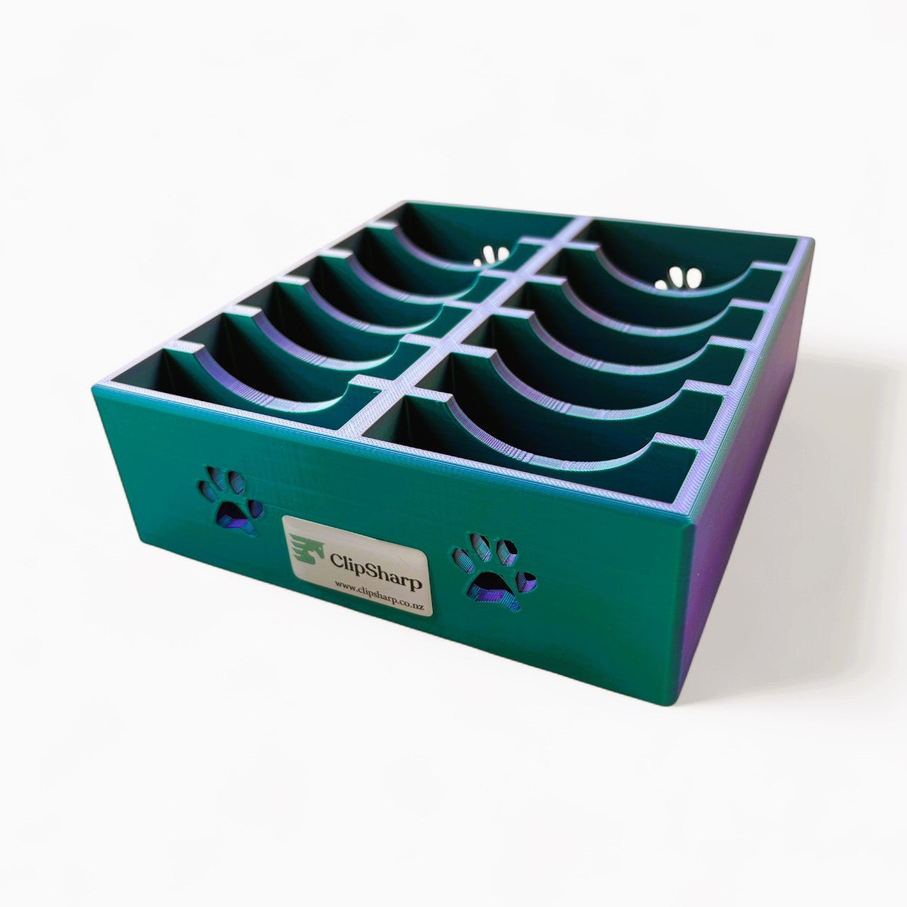 The Clip Sharp Wide Blade Tray is a green plastic organizer with eight curved slots and two paw print cutouts on the side, labeled ClipSharp on the front, designed for holding clipper blades, shown on a white background.